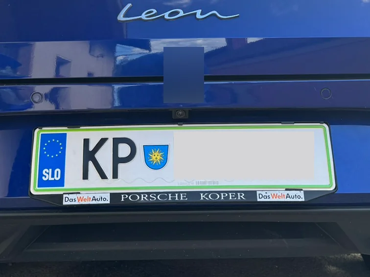 Zadek modrega Seat Leona z oglaševalnim okvirjem prodajalca okoli tablice